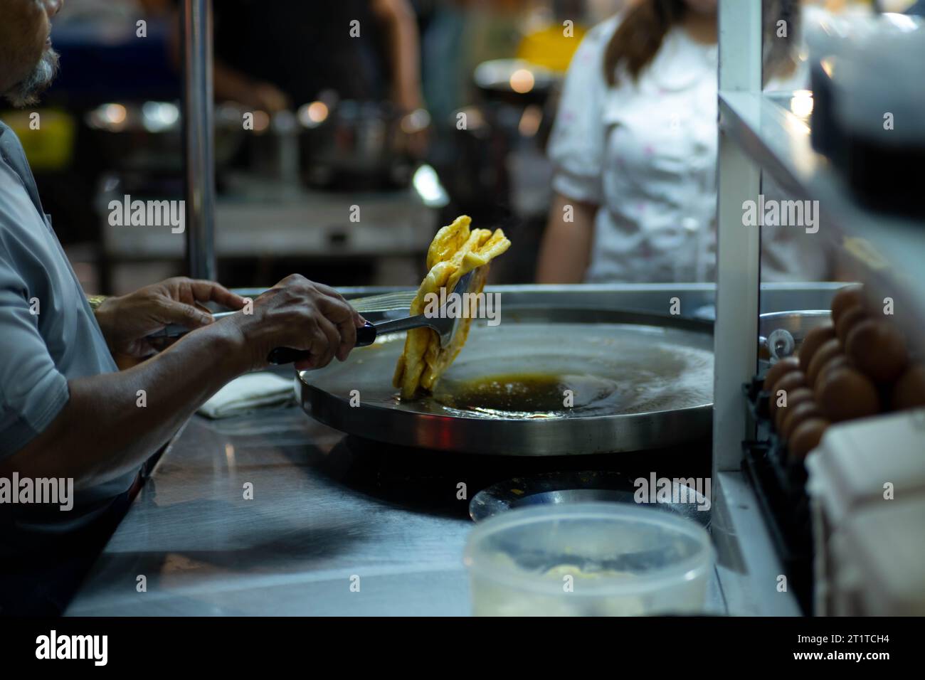 Fabrication de roti, roti battre la farine par roti Maker avec de l'huile. Crêpe thaïlandaise garnie de lait condensé sucré, puis saupoudrer de sucre. Thai Street Foo Banque D'Images