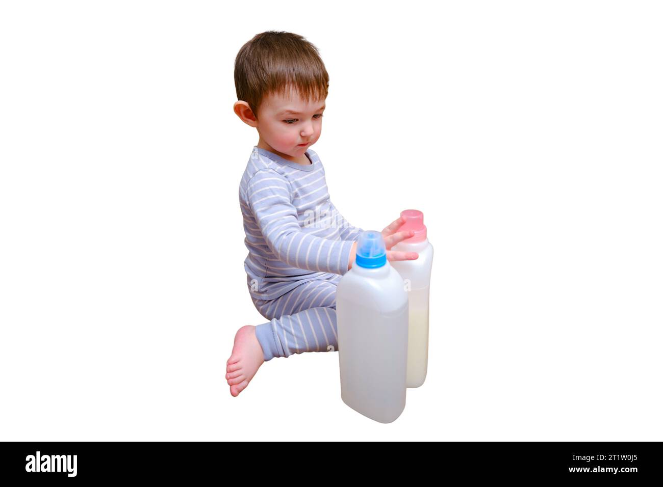 Bébé en bas âge joue avec des produits chimiques ménagers et détergent du placard, isolé sur fond blanc. Enfant garçon avec bouteille de détergent dans la vie à la maison Banque D'Images