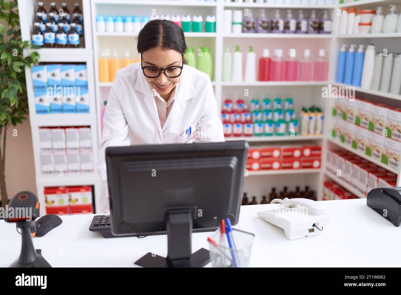 Jeune femme arabe pharmacien souriant confiant en utilisant l'ordinateur à la pharmacie Banque D'Images