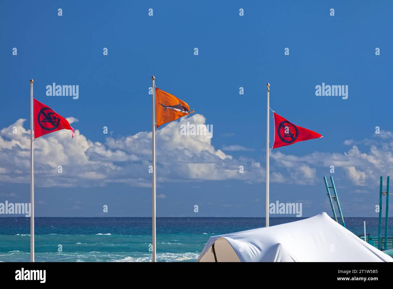 Trois drapeaux d'avertissement brandissant en l'air à la Plage des roches noires à Saint-Gilles les bains pendant le solstice d'été. Les deux drapeaux rouges indiquent Banque D'Images