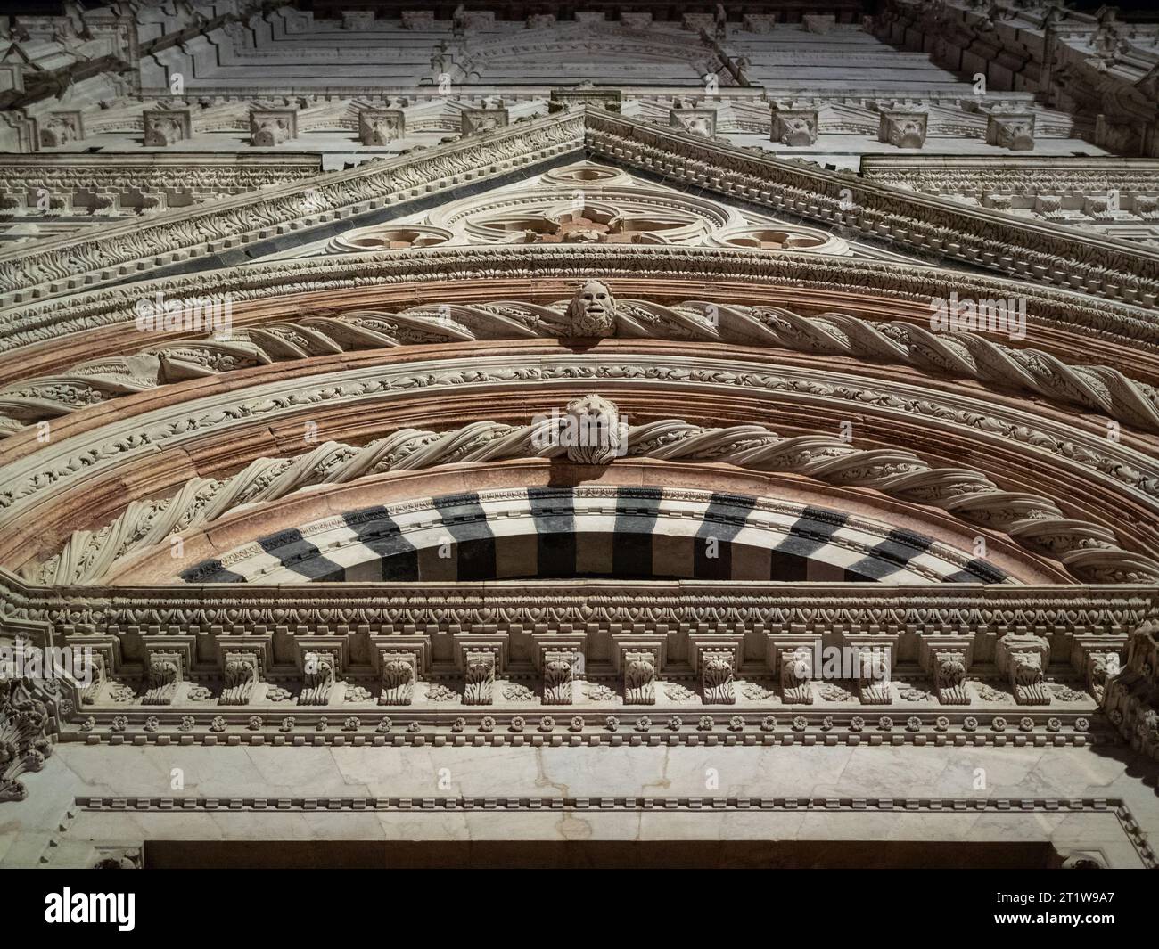 Regardant vers le haut les travaux de sculpture sur pierre sur la façade de Battistero di San Giovanni, Sienne Banque D'Images