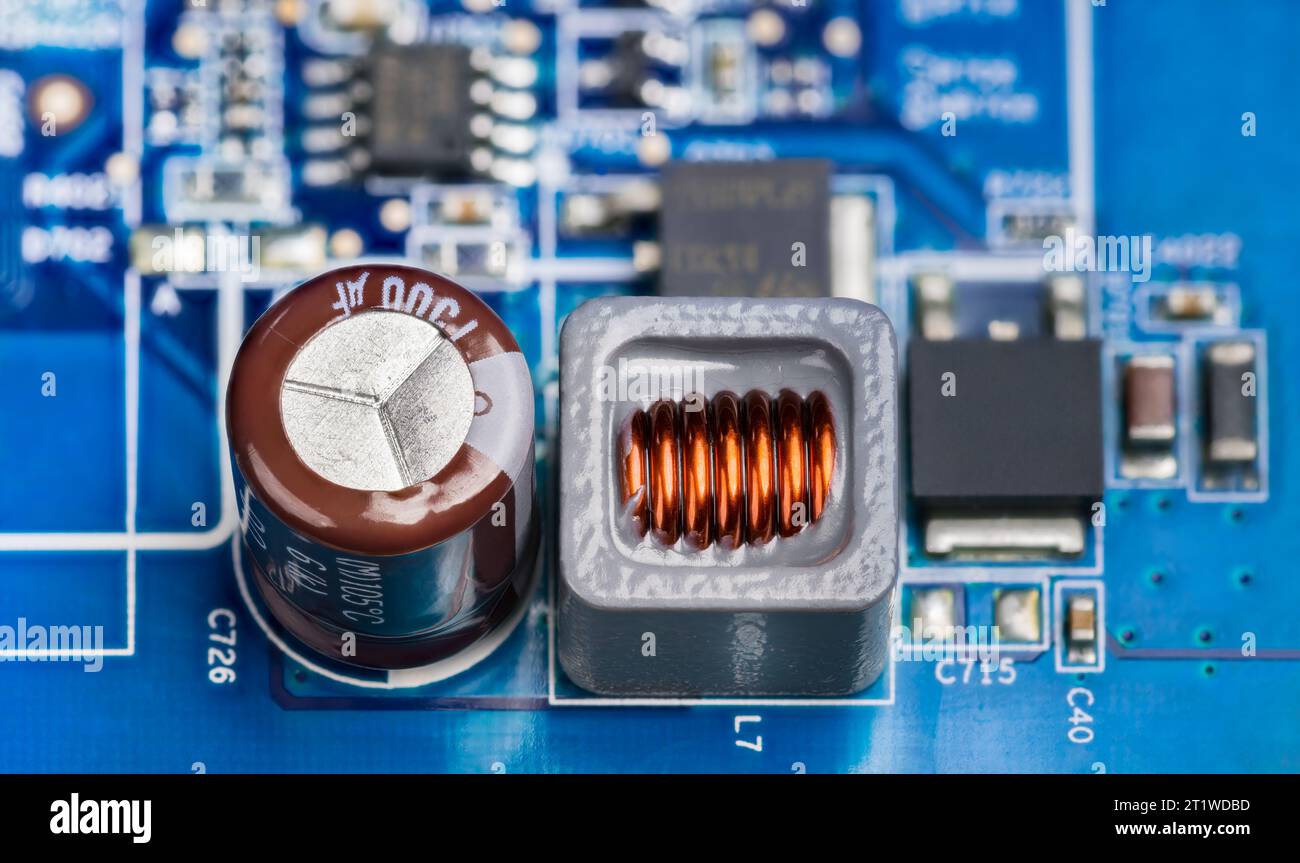 Gros plan des composants électroniques sur la carte de circuit imprimé de l'alimentation. Condensateur électrolytique marron, inductance dans un boîtier gris ou transistors noirs. Banque D'Images