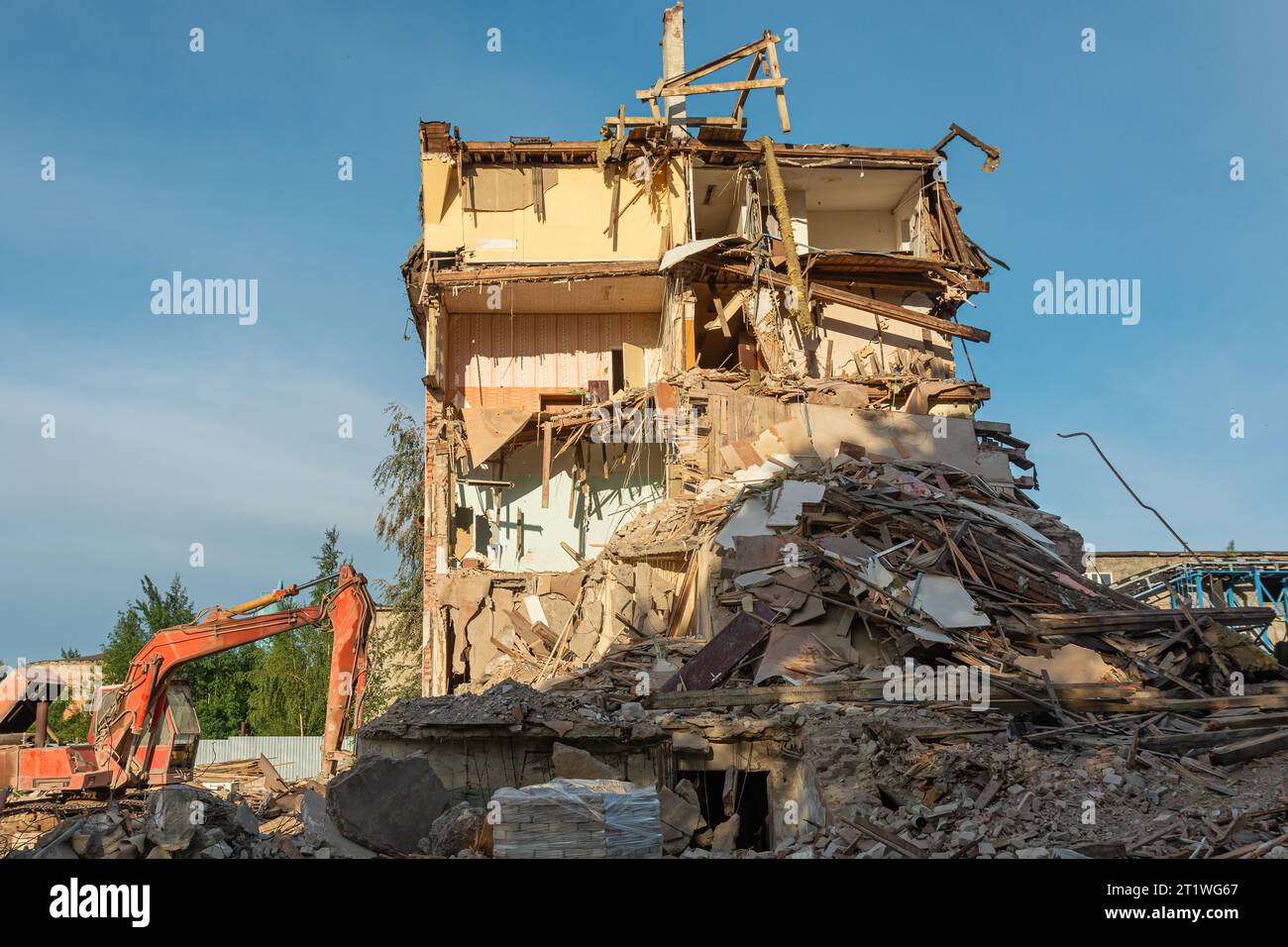 Démolition d'un bâtiment en ruine. Excavatrice casse la vieille maison endommagée par une attaque terroriste, une guerre ou un tremblement de terre pour construire une nouvelle maison. Contexte industriel Banque D'Images