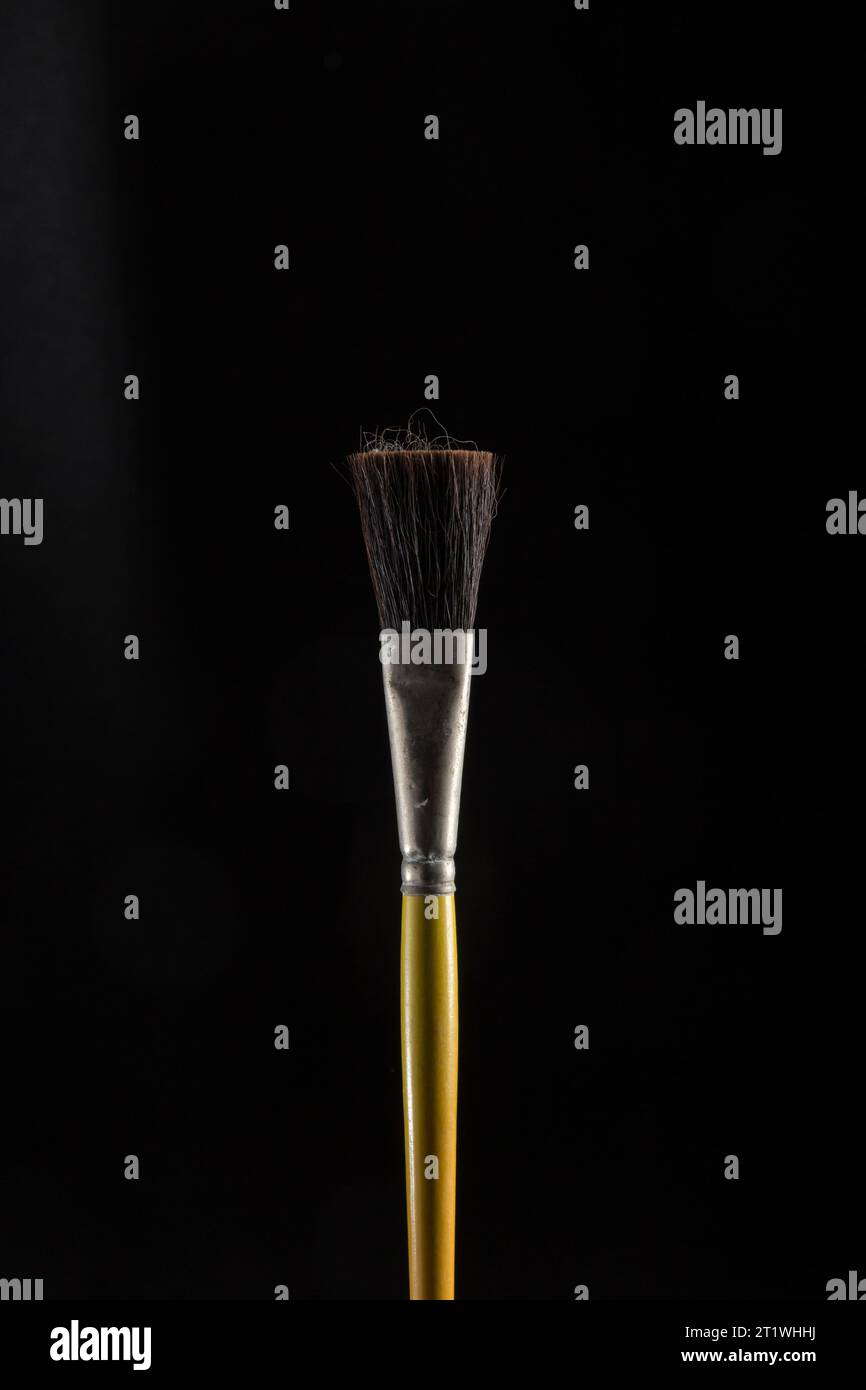 pinceau en bois avec poils bruns expansés, placé sur un fond noir, mettant en évidence une figure stylisée Banque D'Images