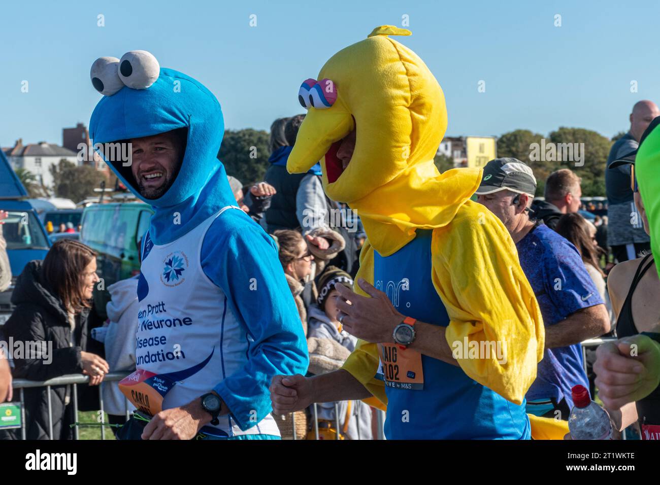 Great South Run, 15 octobre 2023, Portsmouth, Hampshire, Angleterre, ROYAUME-UNI. Des milliers de concurrents ont couru dans le 10 Mile Great South Run qui a commencé et s'est terminé à Southsea, Portsmouth. En plus des coureurs d'élite, beaucoup d'autres personnes ont participé à la course pour la charité ou pour leurs clubs. Sur la photo : deux hommes vêtus de muppet montrent costume de robe fantaisie, le monstre de cookie et les costumes de grand oiseau Banque D'Images