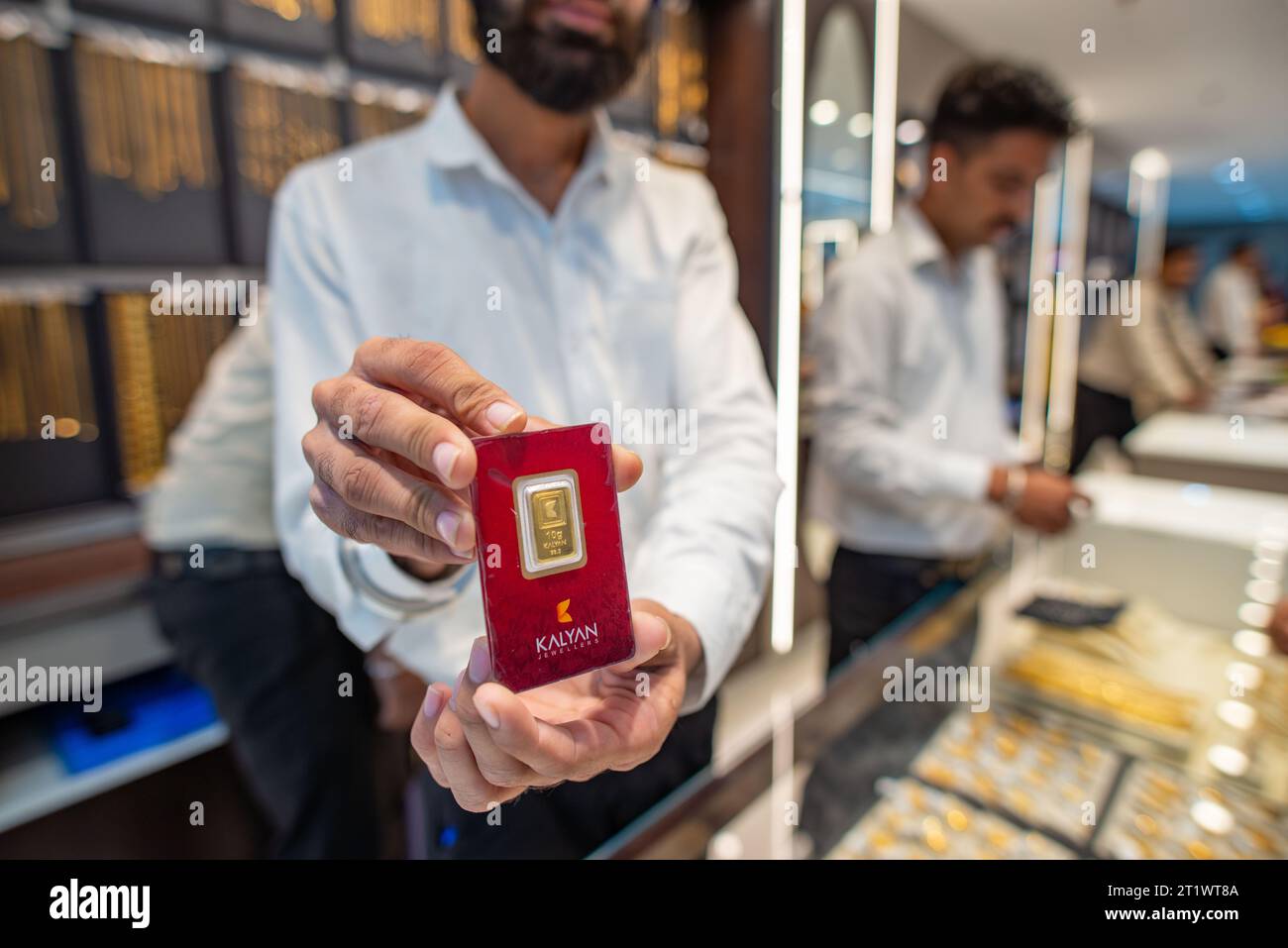 New Delhi, Inde. 15 octobre 2023. Un employé montrant la pièce d'or de 10 grammes aux clients, le jour du lancement de la nouvelle salle d'exposition de bijoux Kalyan à Karol Bagh, New Delhi, Inde. Kalyan Jewelers est une chaîne indienne de showrooms de bijoux. Il a été fondé par T. S. Kalyanaraman en 1993. (Photo Pradeep Gaur/SOPA Images/Sipa USA) crédit : SIPA USA/Alamy Live News Banque D'Images