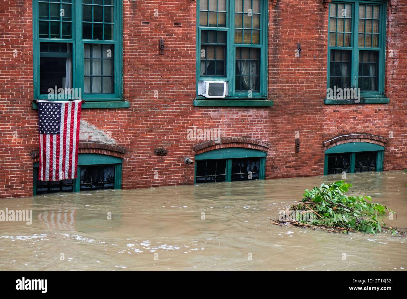 Un drapeau américain pend d'une fenêtre d'un appartement juste au-dessus du niveau des eaux de crue à Montpelier VT, USA. Banque D'Images