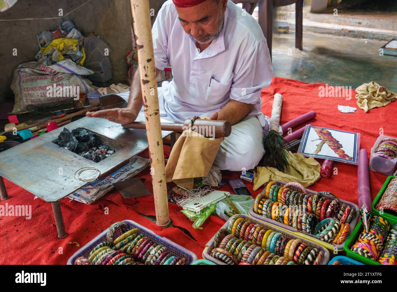 Jaipur, Rajasthan, Inde, 09/16/2023, Temple Harshat Mata adjacent au Baori. Un homme local fabriquant des bijoux de bracelet. Les bracelets sont très colorfu Banque D'Images