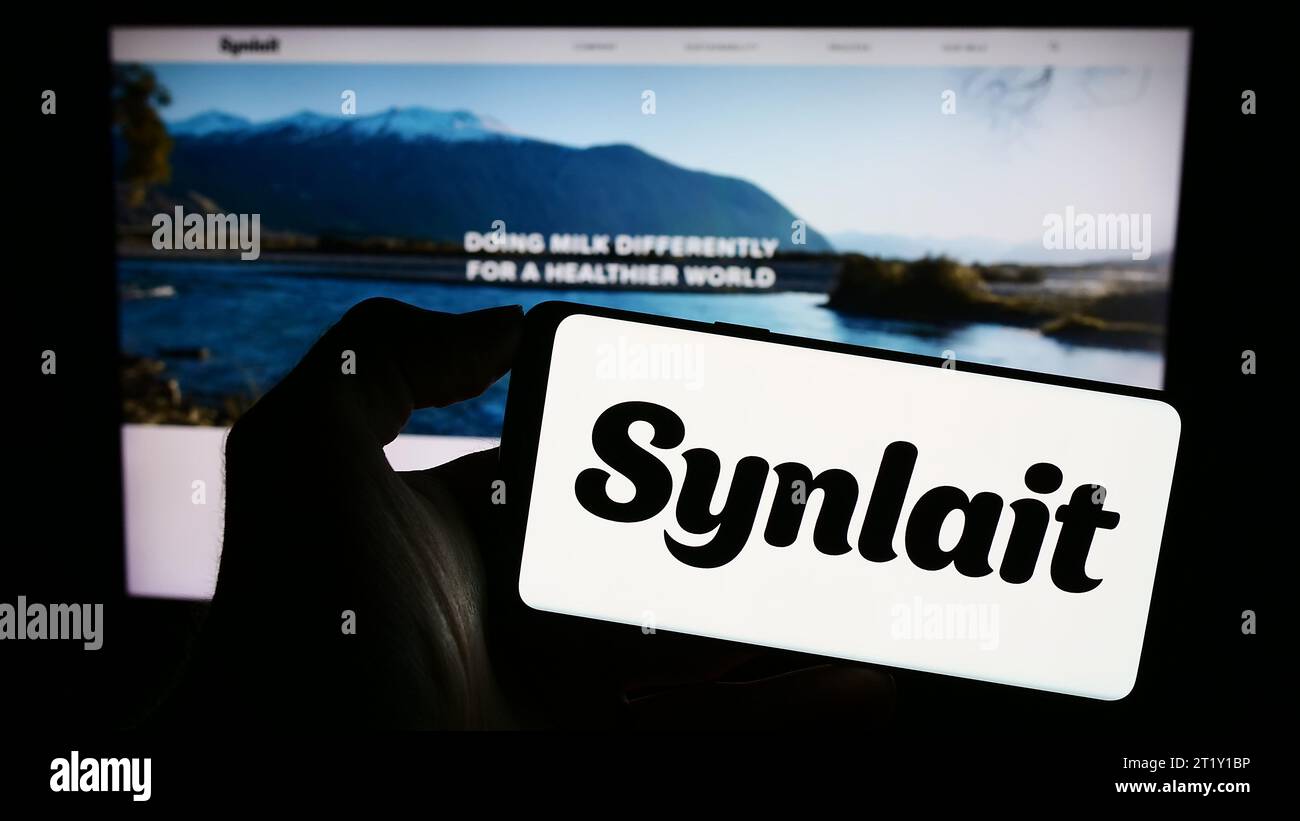 Personne tenant un smartphone avec le logo de la société de nutrition néo-zélandaise Synlait Limited devant le site Web. Concentrez-vous sur l'affichage du téléphone. Banque D'Images
