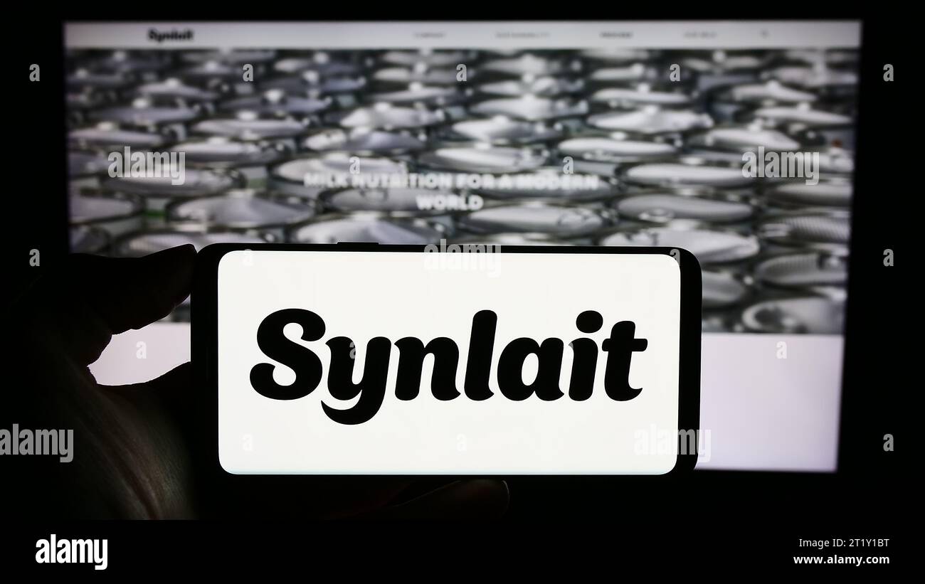 Personne tenant un téléphone portable avec le logo de la société de nutrition de Nouvelle-Zélande Synlait Limited devant la page Web de l'entreprise. Concentrez-vous sur l'affichage du téléphone. Banque D'Images