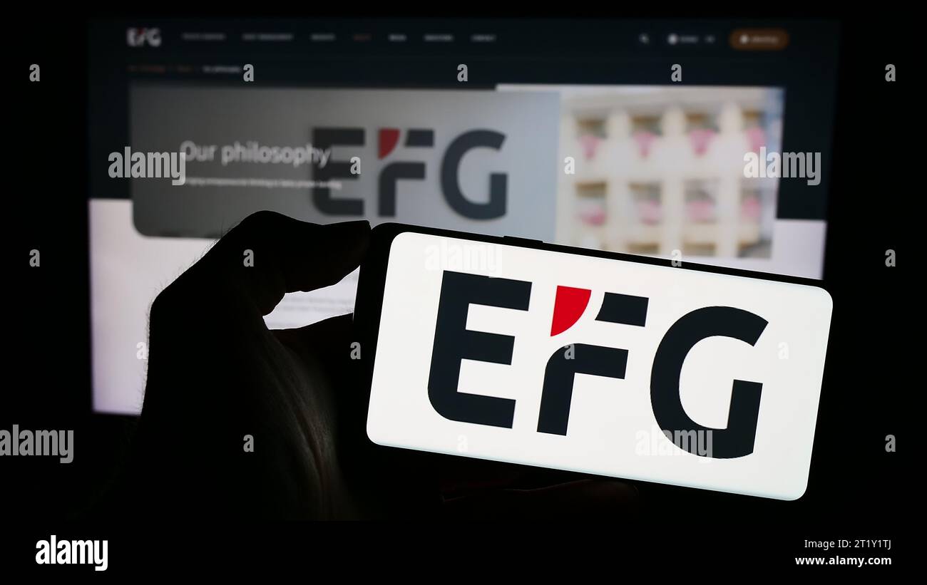 Personne détenant un smartphone avec le logo de la banque privée suisse EFG International AG devant le site Web. Concentrez-vous sur l'affichage du téléphone. Banque D'Images