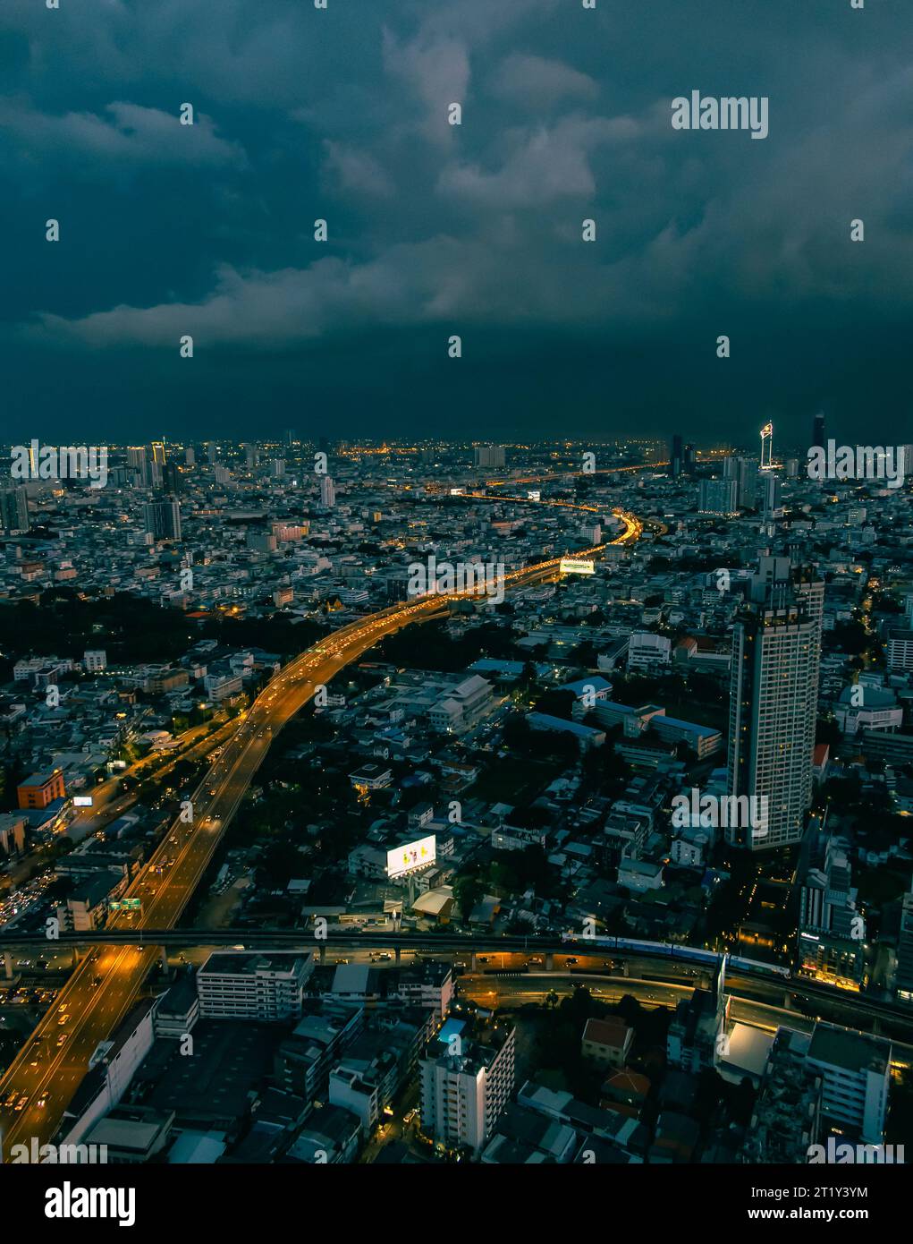 Coucher de soleil sur Bangkok. Les routes brillent en orange avec des lumières de voiture. Les nuages d'orage s'accumulent. Banque D'Images