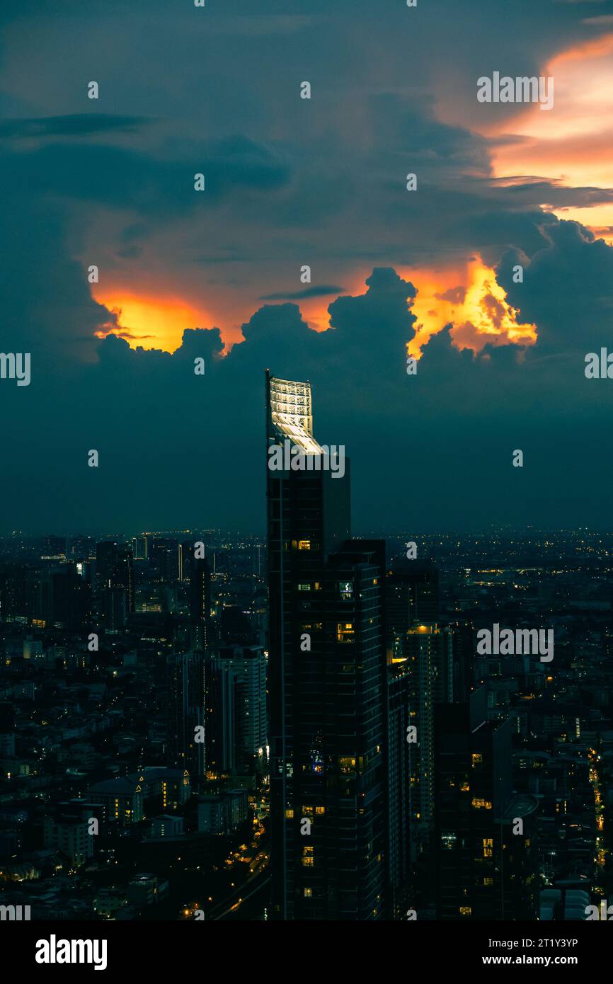 Coucher de soleil sur Bangkok. Ciel orange et nuages spectaculaires. Ornge lumières dans les fenêtres. Banque D'Images