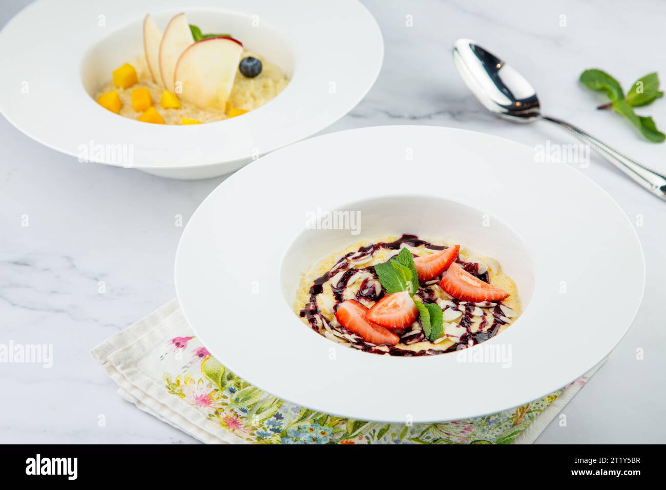 porridge avec fraises, menthe et confiture de baies dans une assiette blanche, vue de côté Banque D'Images