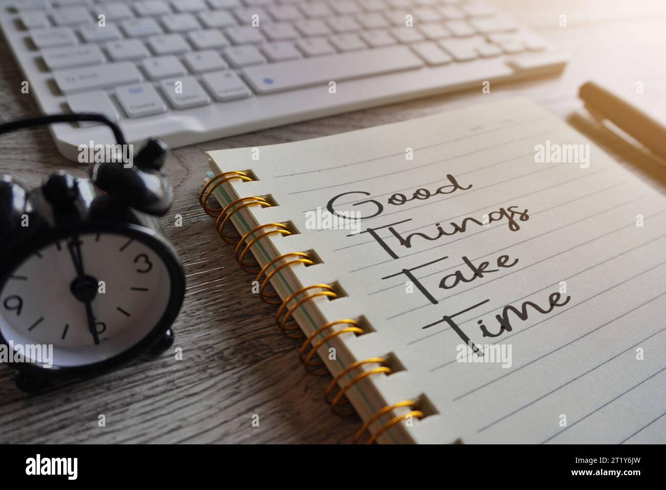 Gros plan de l'image de cahier avec le texte DE BONNES CHOSES PRENNENT LE TEMPS, l'horloge et le stylo sur la table. Concept de motivation Banque D'Images