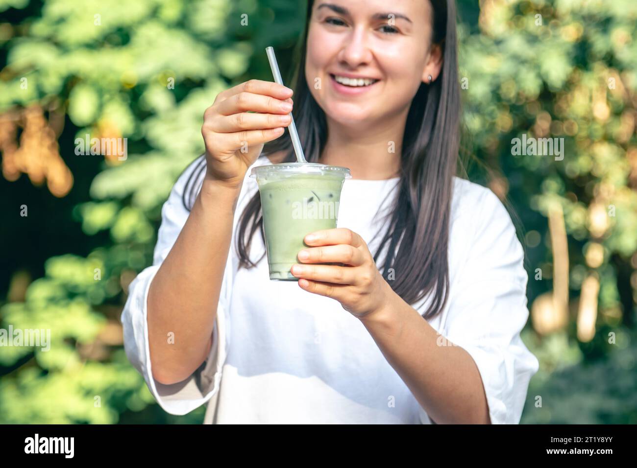 Femme élégante buvant du matcha latte dans le parc. Banque D'Images