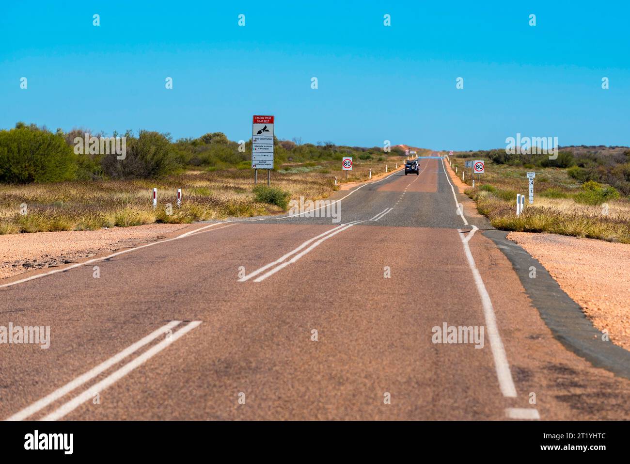 Un panneau d'avertissement multilingue de ceinture de sécurité sur une autoroute entre Alice Springs (Mparntwe) et Kings Canyon dans le territoire du Nord de l'Australie Banque D'Images