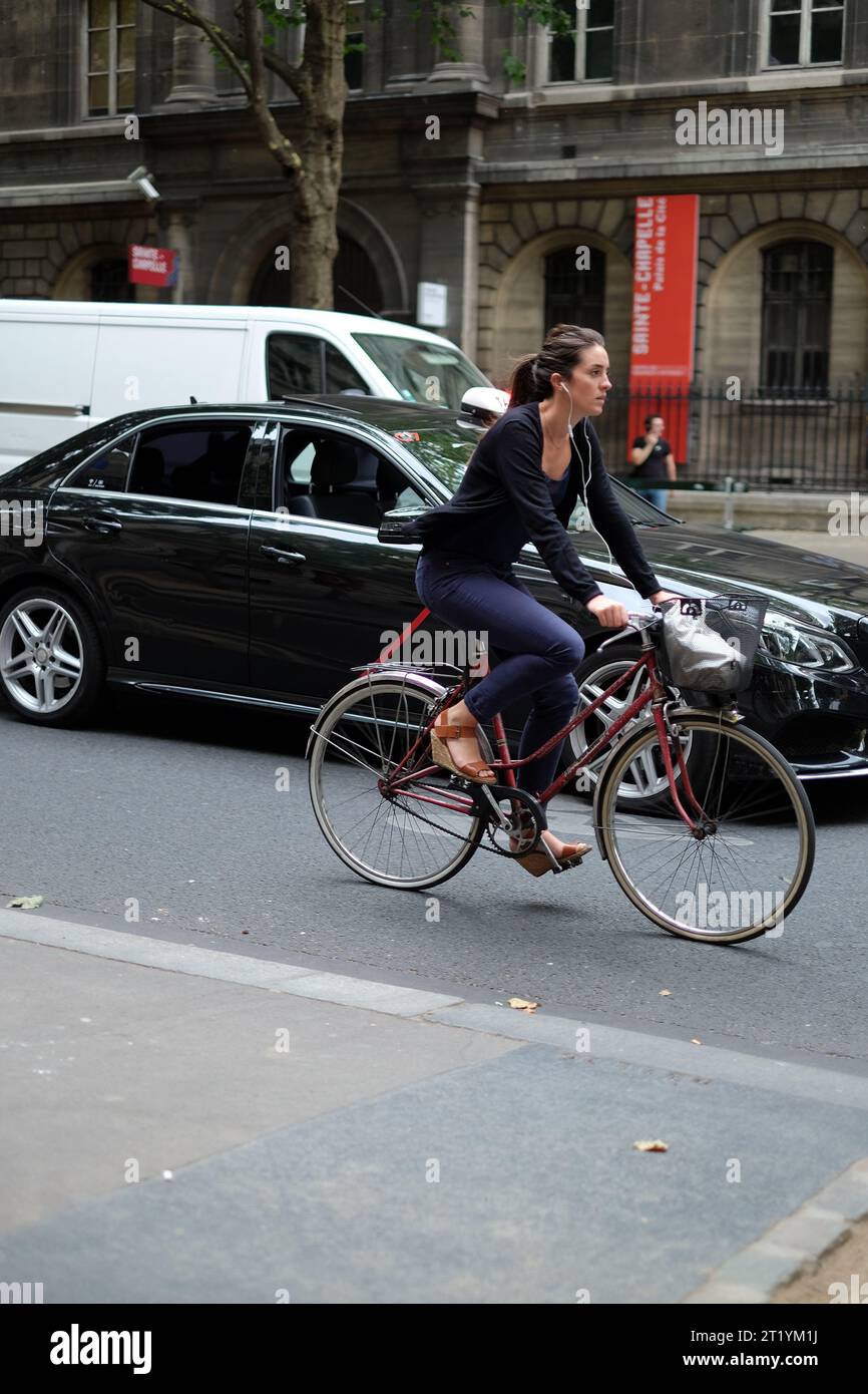 Une jeune femme cycliste élégante roulant dans la circulation sur un vieux vélo de cadre de dames avec un panier de guidon de fil sur le Boulevard du Palais, Paris, France Banque D'Images