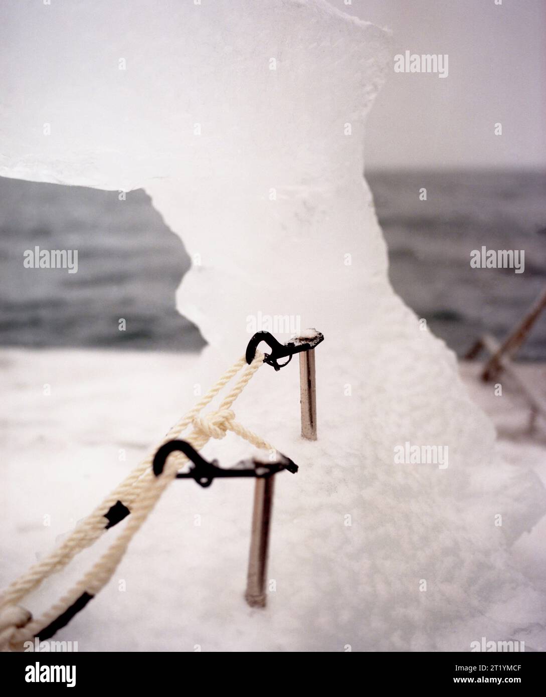 Deux vis à glace dans un gros morceau de glace à l'avant d'un bateau enneigé dans les eaux de la baie Prince William, en Alaska. Banque D'Images