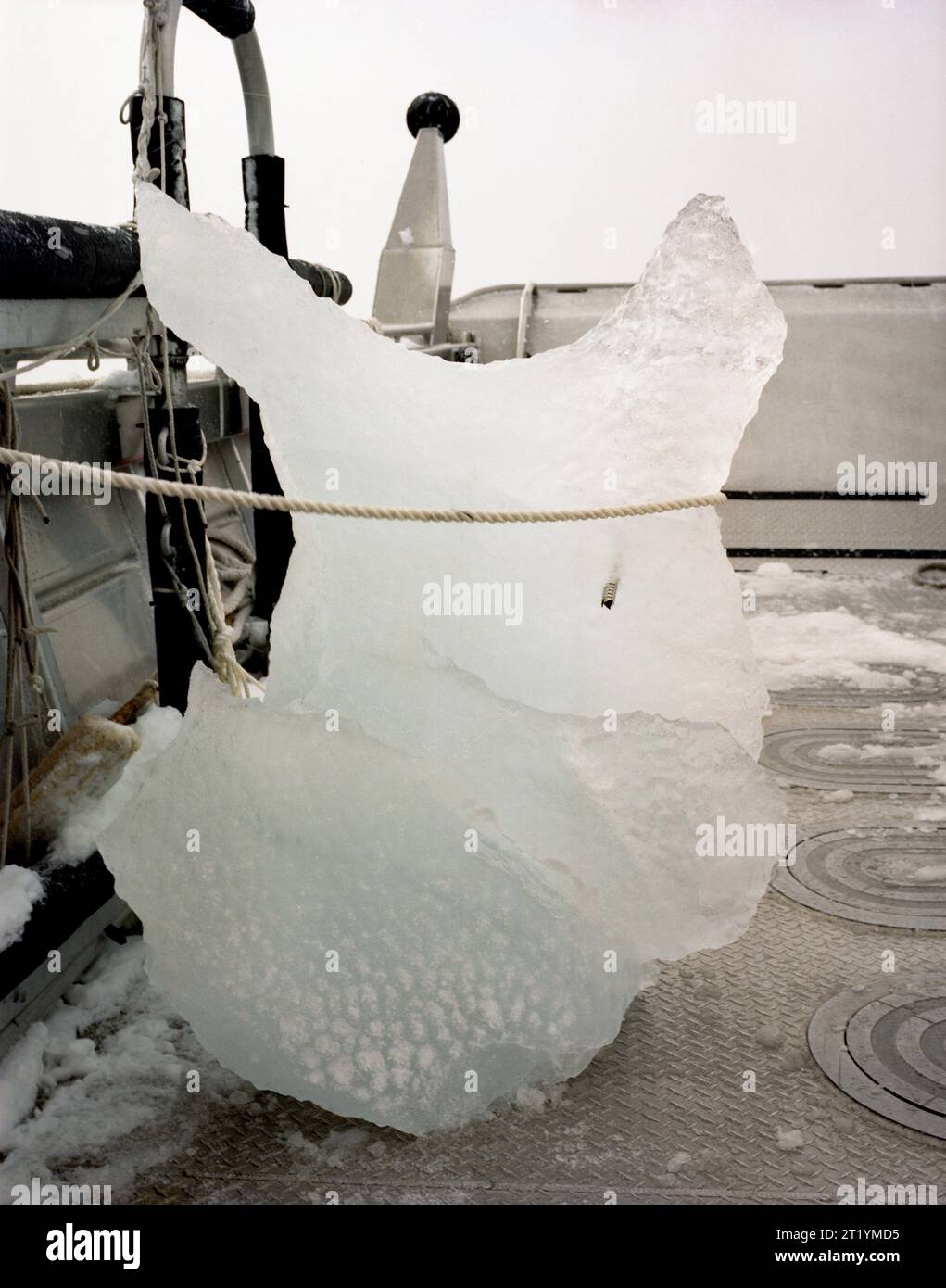 Une vis à glace dans un gros morceau de glace à l'avant d'un bateau couvert de neige dans les eaux de Prince William Sound, Alaska. Banque D'Images