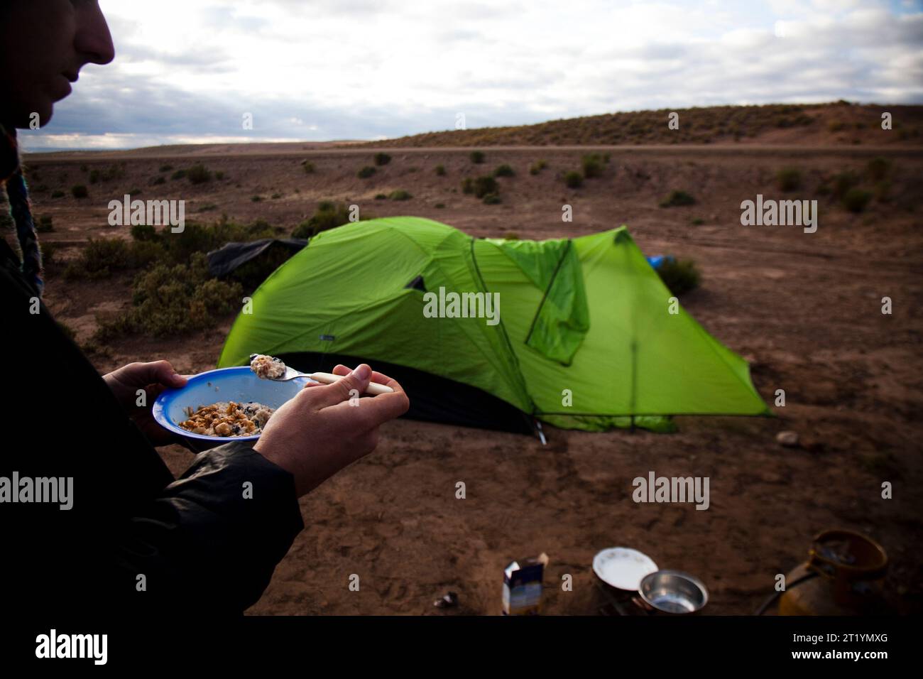 Un homme mange de la farine d'avoine après s'être réveillé du camping dans le désert. Banque D'Images