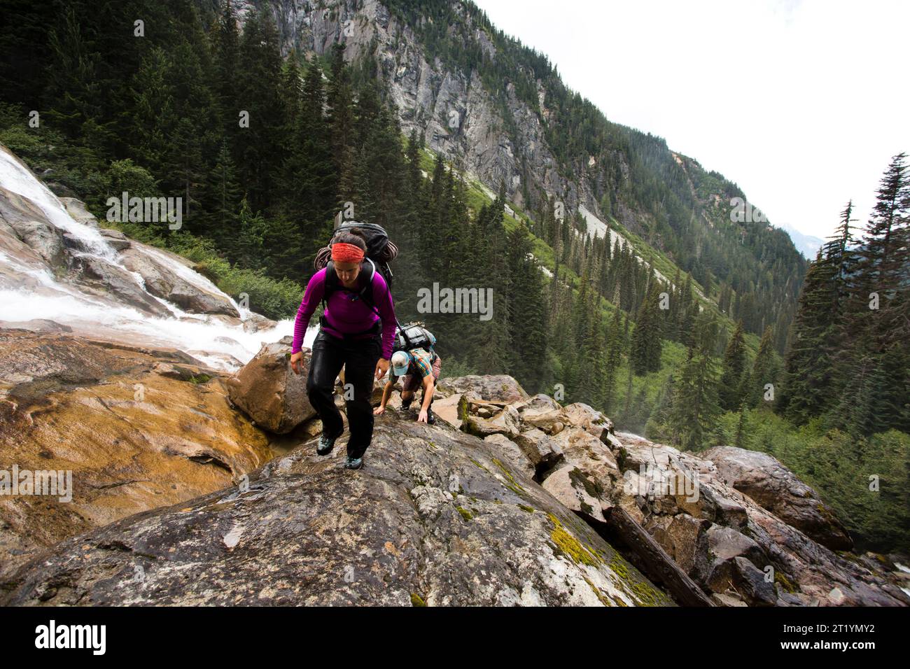 Les randonneurs escaladent des rochers le long d'une cascade dans le parc national North Cascades de l'État de Washington. Banque D'Images