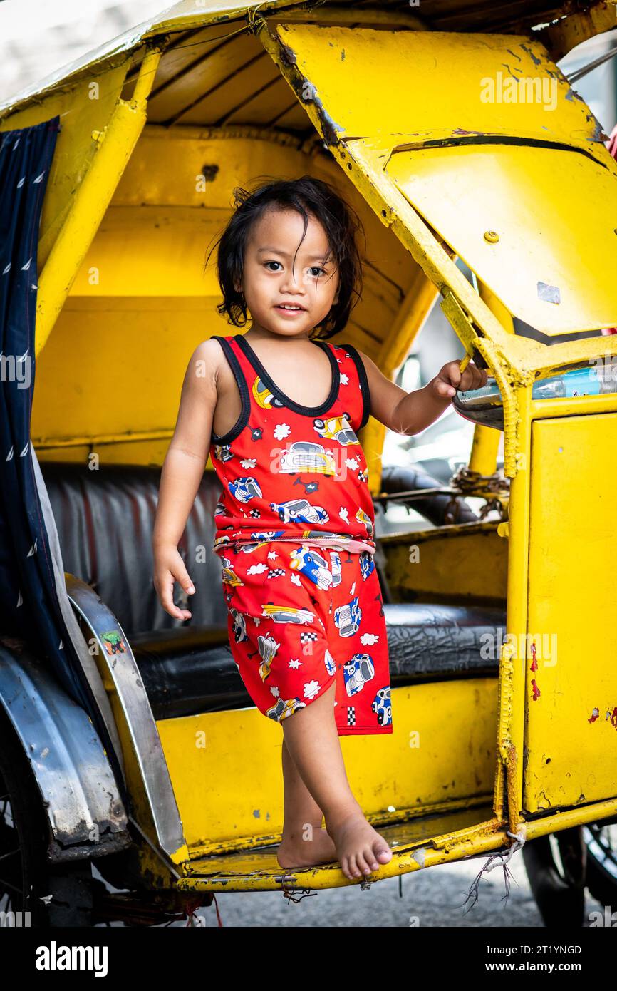 Une jolie fille philippine joue sur son père tricycle, pédicab ou pousse-pousse à Ermita, Manille, Philippines. Banque D'Images
