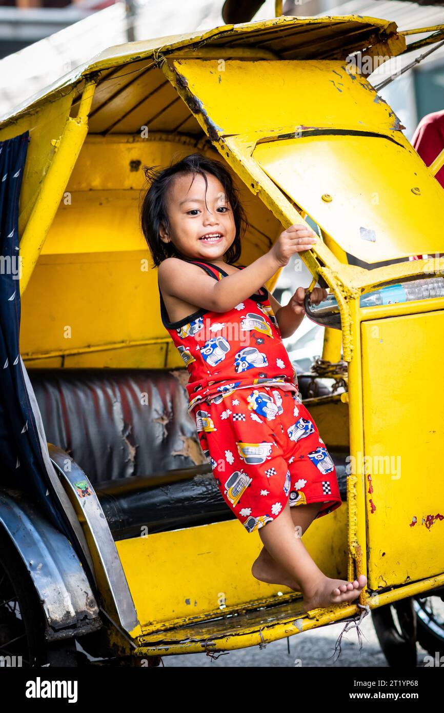 Une jolie fille philippine joue sur son père tricycle, pédicab ou pousse-pousse à Ermita, Manille, Philippines. Banque D'Images