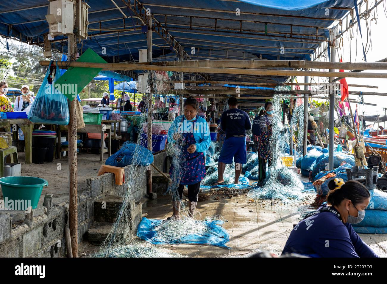 Thaïlande, province de Rayong, Pan Phe : nageur bleu pêche au crabe. Des filets sont réparés dans le port Banque D'Images