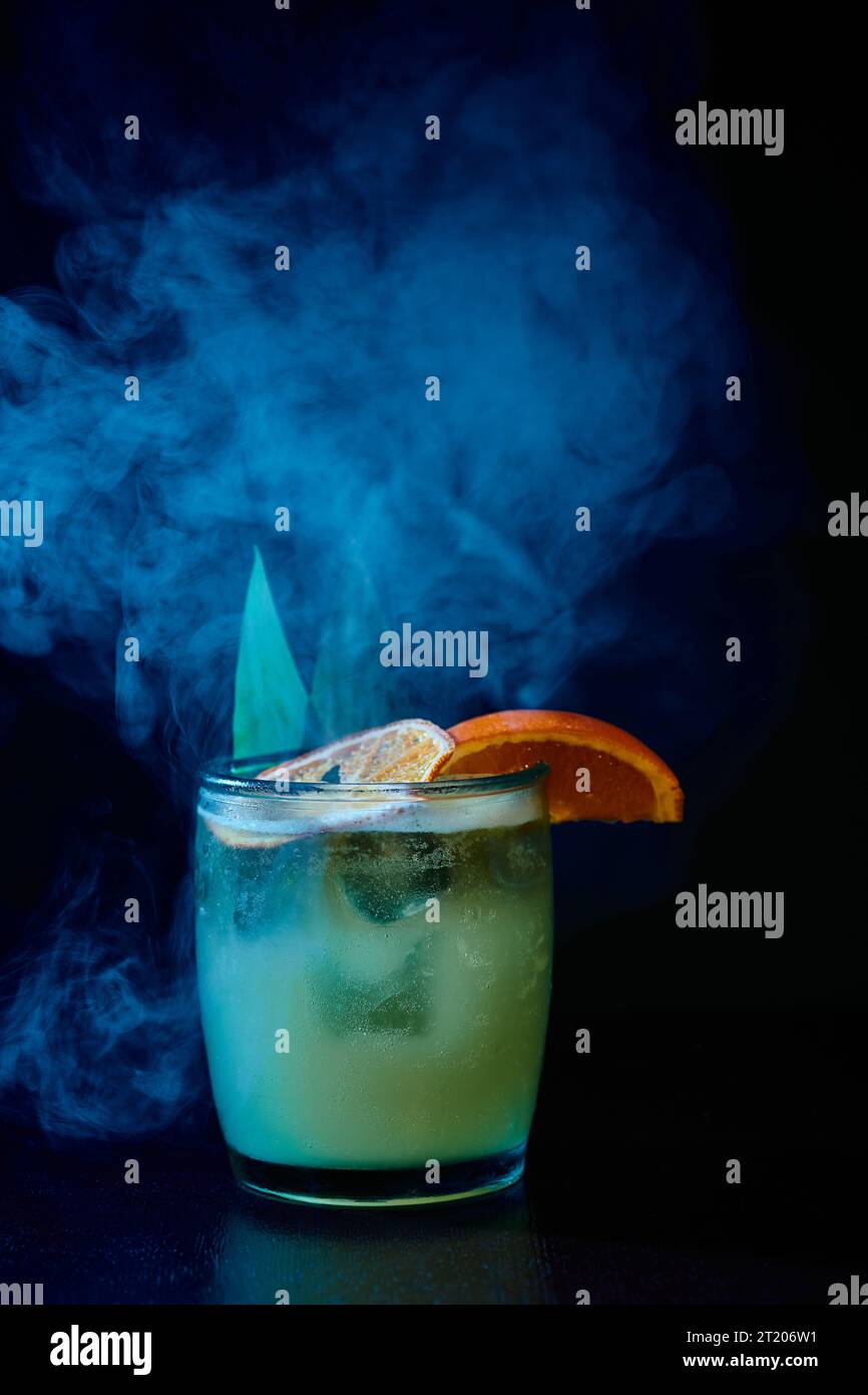 cocktail sophistiqué à l'ancienne avec garniture sur fond noir fumé, concept Banque D'Images