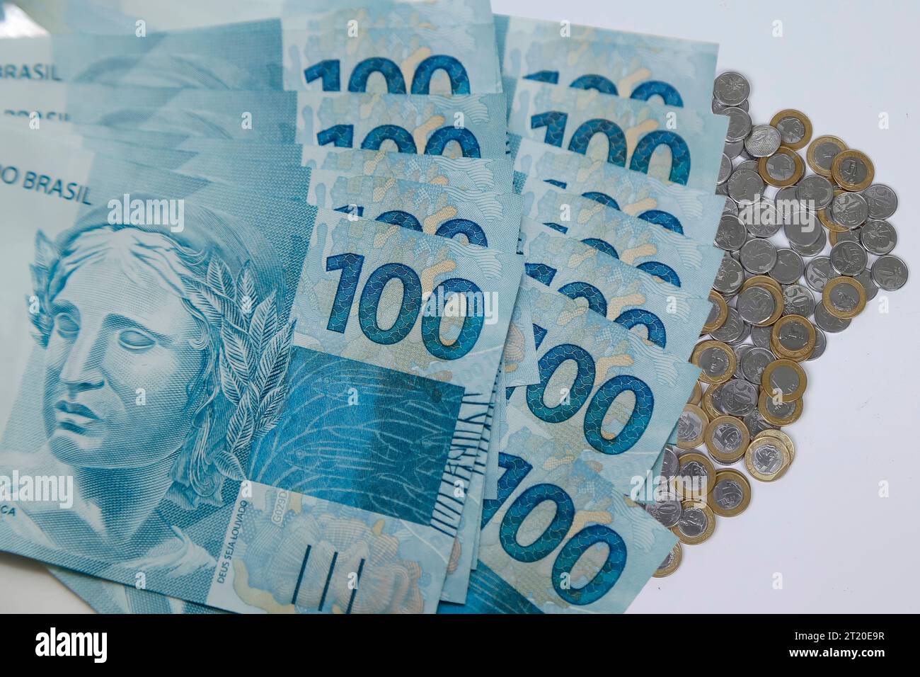 Plusieurs centaines de billets et pièces de monnaie reais du Brésil sur fond blanc neutre Banque D'Images