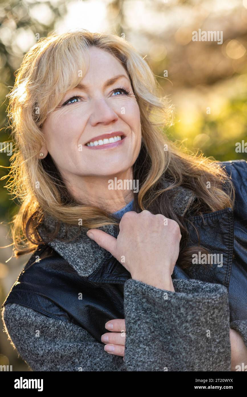 Femme d'âge moyen souriant en bonne santé dehors au coucher du soleil Banque D'Images