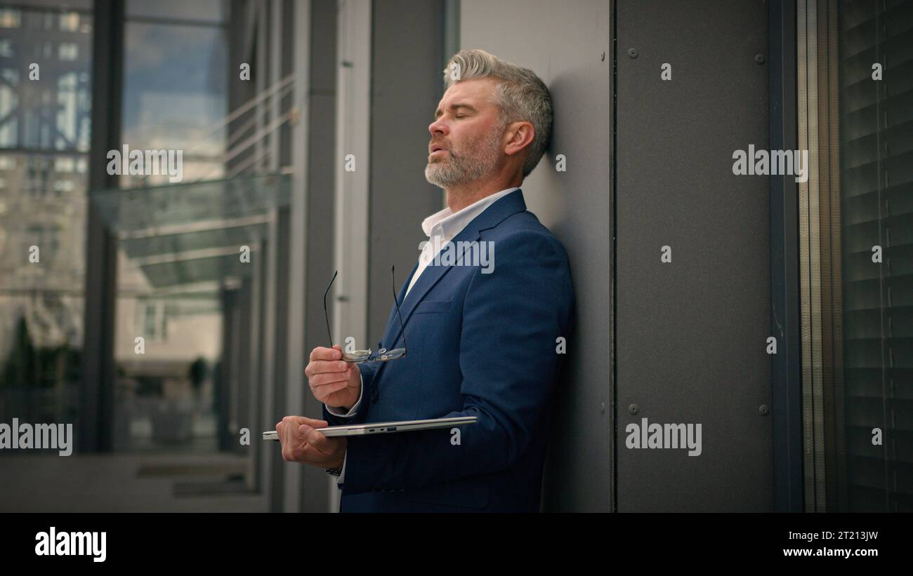 Fatigué épuisé vieux homme d'affaires caucasien vieux employeur mature homme d'affaires senior masculin d'âge moyen Manager avec ordinateur portable finir la ville de travail à l'extérieur Banque D'Images