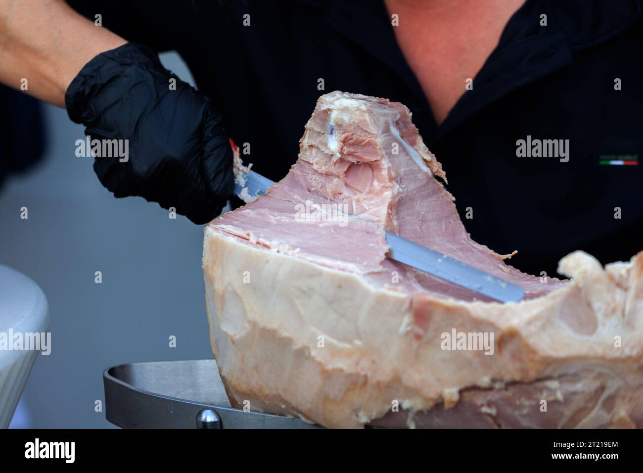 Gros plan des mains d'un serveur expert tout en tranchant le jambon cuit typique de Triestine Banque D'Images