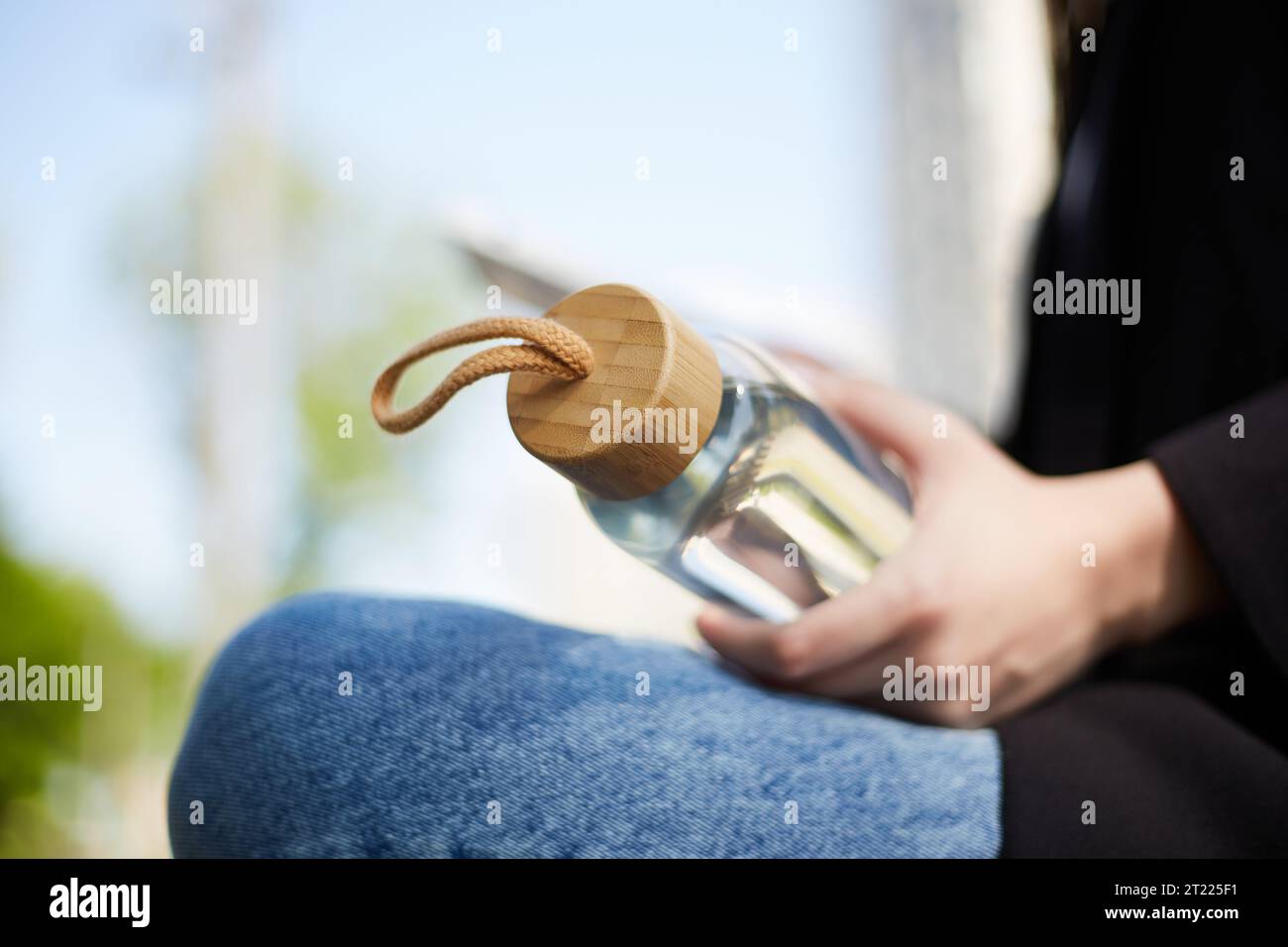 Femme assise sur un banc avec une bouteille en verre réutilisable à la main. Concept de style de vie durable Banque D'Images