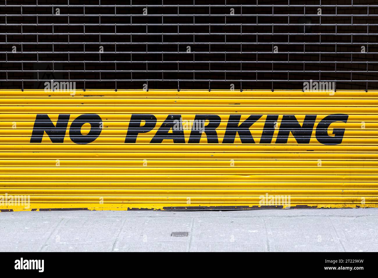 Un panneau jaune No parking sur une porte de volet roulant industriel Banque D'Images