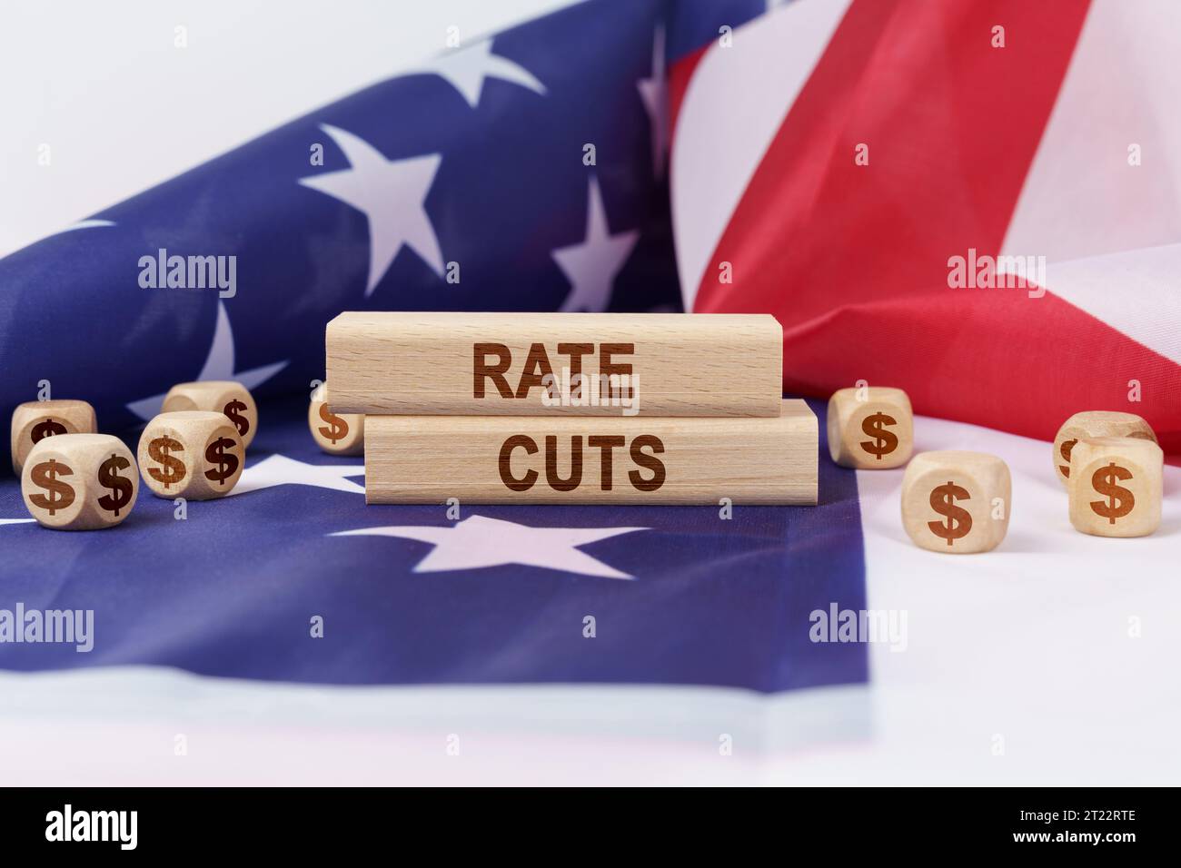 Concept d'économie et de finance. Sur le drapeau des États-Unis se trouvent des cubes avec le symbole du dollar et des matrices en bois avec l'inscription - Rate Cuts. Banque D'Images