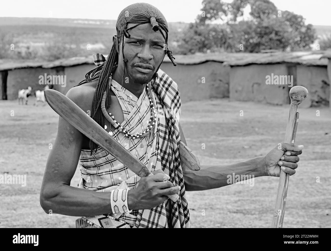 Homme tribal de Maasai Mara portant une épée courte, un bâton et un club divertissant les visiteurs avec ses coutumes traditionnelles dans son village Banque D'Images