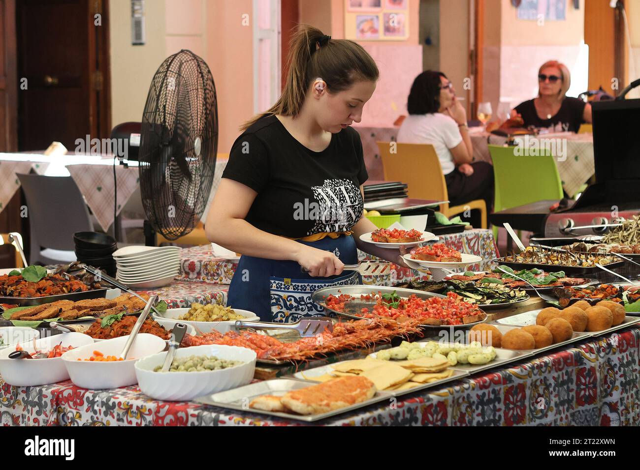 Une serveuse prépare des plats de nourriture dans un café de rue dans le marché Ballaro, Palerme, Sicile Banque D'Images