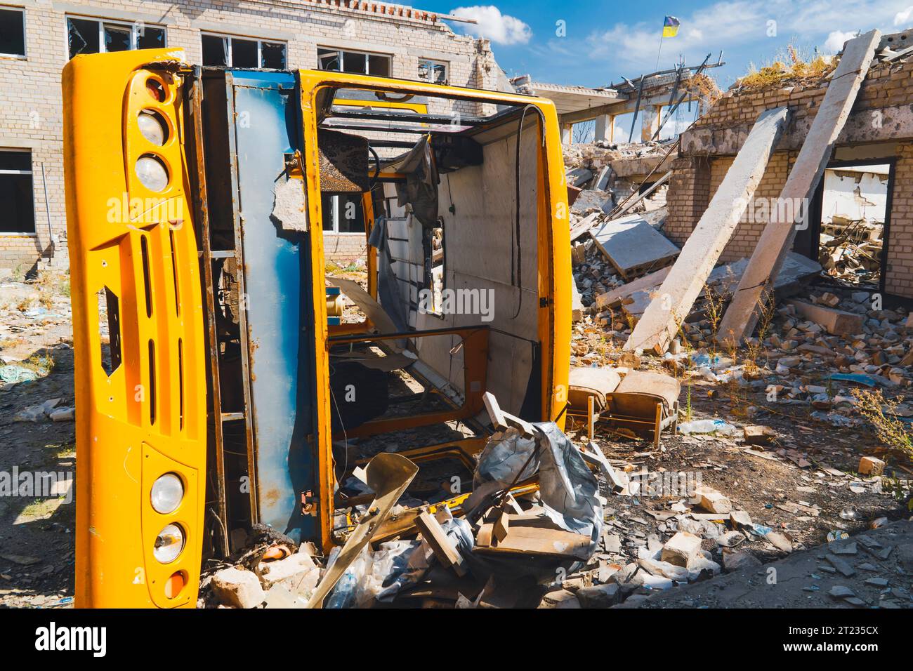 Autobus scolaire jaune détruit dans la cour d'une école détruite. Guerre en Ukraine. Invasion russe de l'Ukraine. Terreur des civils Banque D'Images