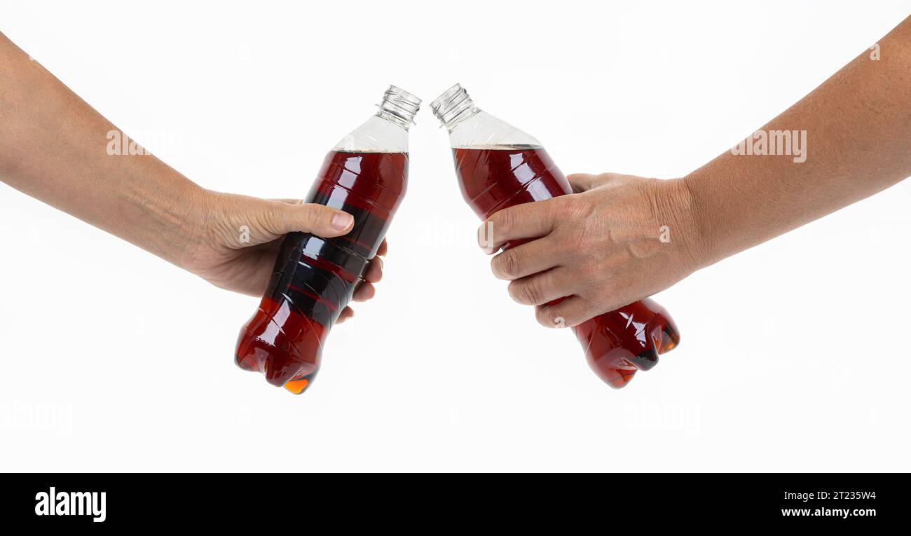 Gros plan recadré des mains d'un jeune couple, de deux amis, de la famille, d'un homme et d'une femme tenant des bouteilles transparentes, clinquant des verres, faisant toa Banque D'Images