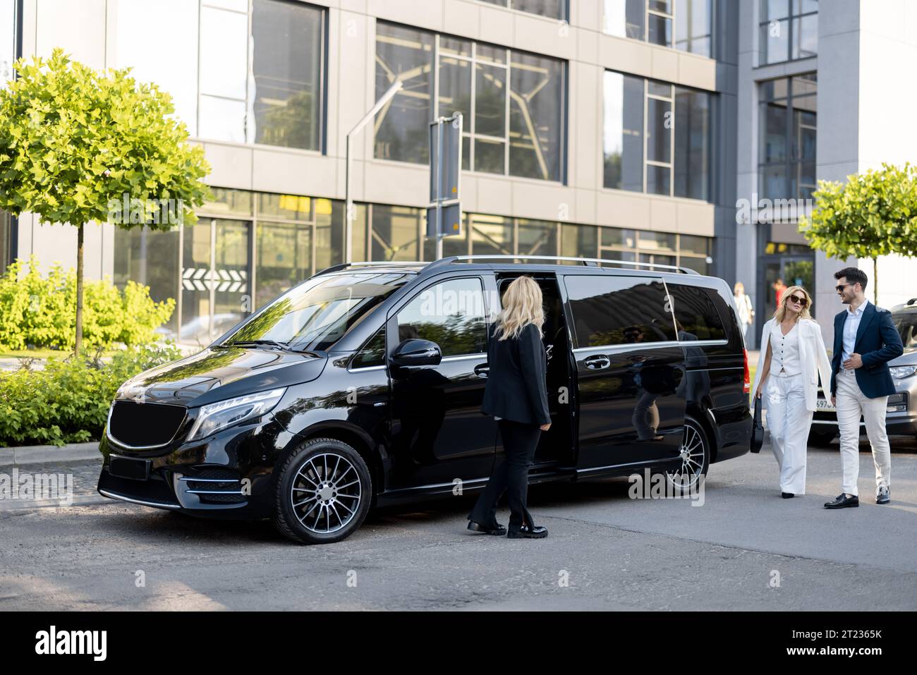Femme chauffeur attend un gens d'affaires près de minivan taxi Banque D'Images