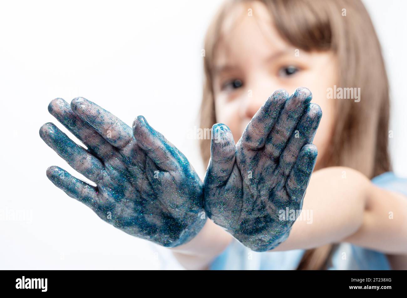 Enfant heureux avec des mains peintes brillantes paume de couleur bleue Banque D'Images