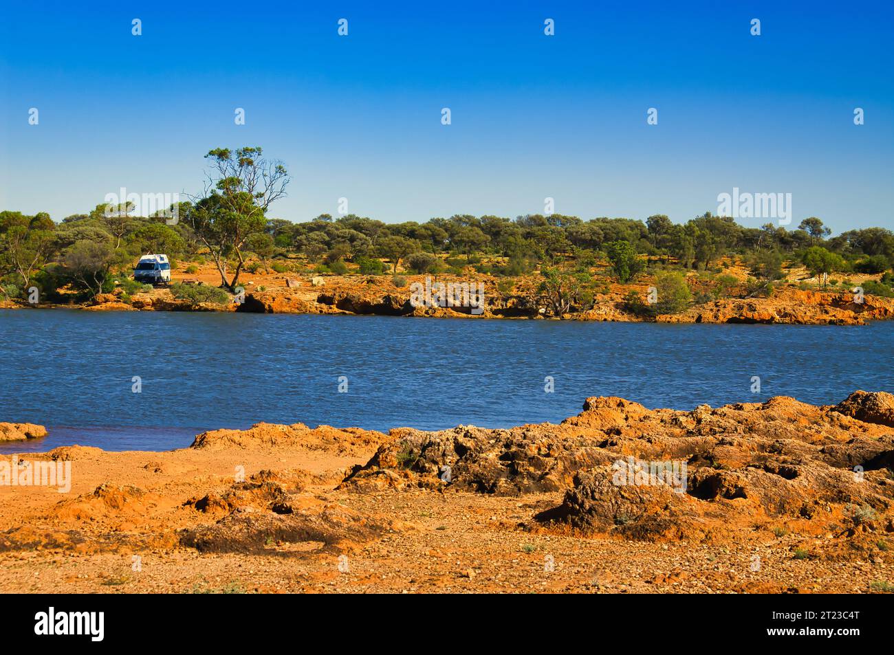 De l'eau dans l'outback australien sec et rouge, petit camping-car garé de l'autre côté du lac. Réserve naturelle de Niagara Dam, Menzies, Australie occidentale. Banque D'Images