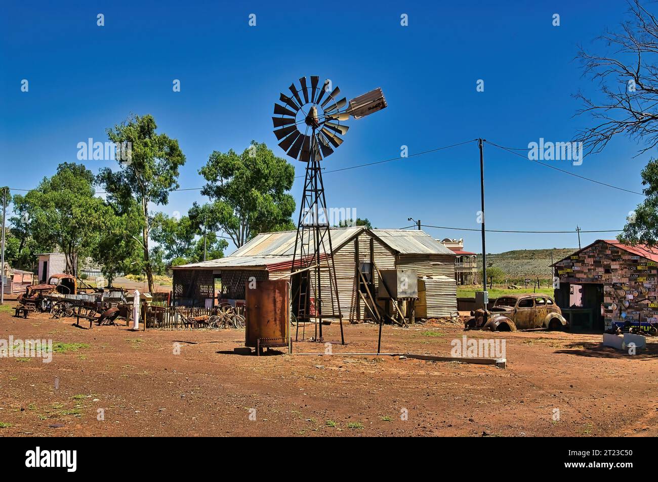 Maison en tôle ondulée, vieilles voitures rouillées et un moulin à vent dans la ville fantôme de Gwalia dans le Grand désert Victoria, comté de Leonora, Australie occidentale Banque D'Images