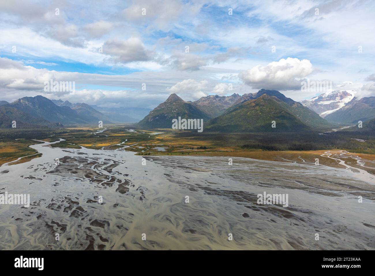 Une vue aérienne d'une rivière tressée qui coule à travers une vallée entourée de montagnes, mettant en valeur la beauté naturelle et le paysage dynamique de la région. Banque D'Images