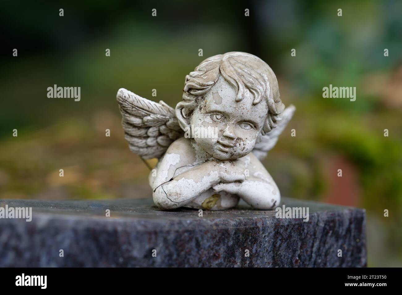 petite figurine de putto endommagée et altérée avec des ailes repose sur une pierre tombale Banque D'Images
