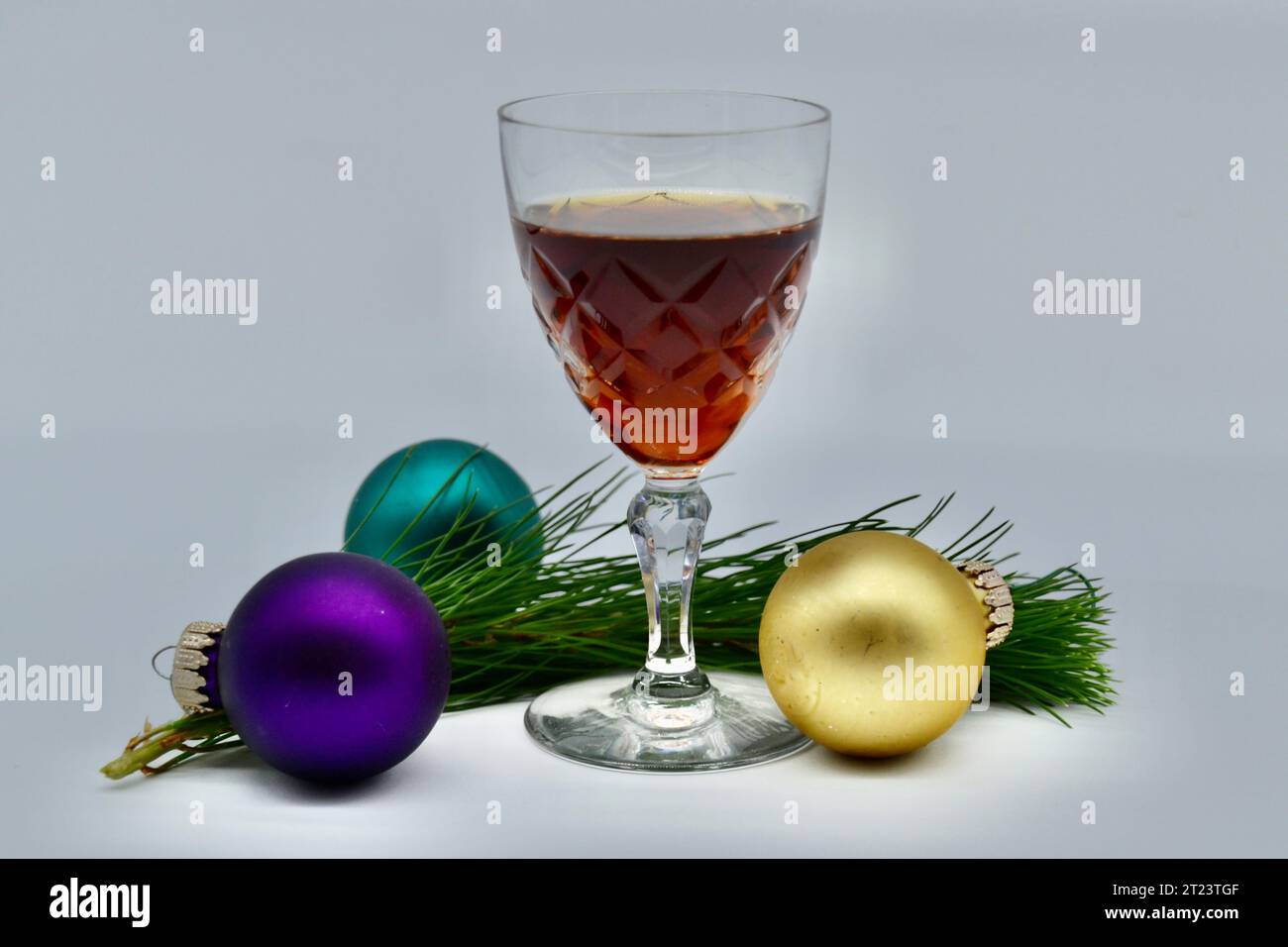 Trois boules de Noël colorées et une branche de sapin de Noël épicéa et un verre de Porto en studio photographié avec fond blanc Banque D'Images
