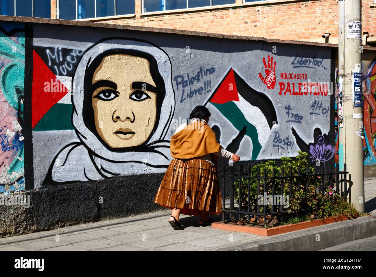 Une femme Aymara ou une cholita vêtue de vêtements traditionnels passe devant une fresque montrant son soutien à une Palestine libre et exigeant la fin de l'holocauste palestinien, district de Miraflores, la Paz, Bolivie. La photo a été prise en septembre 2018. Banque D'Images