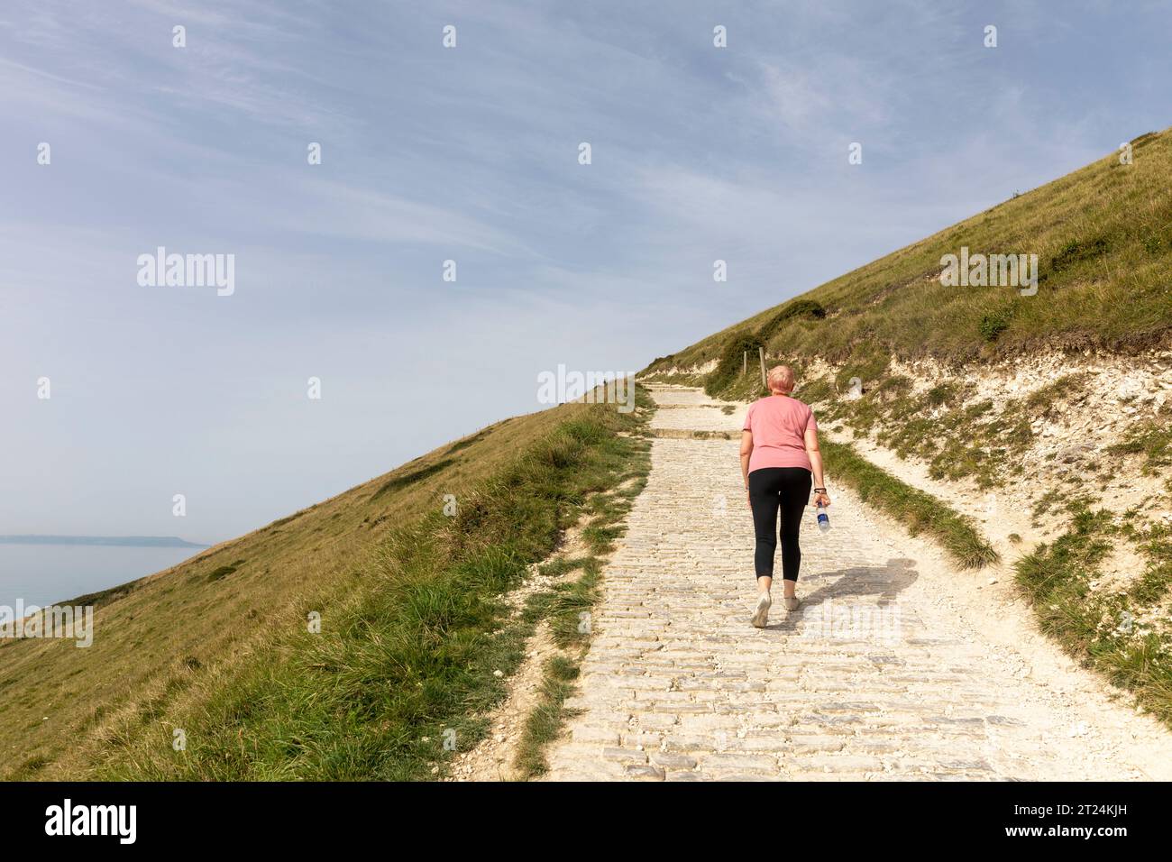 Modèle libéré femme dame marchant de Lulworth Cove à Durdle Door sur la côte jurassique du Dorset le long du chemin côtier sud-ouest, Angleterre, Royaume-Uni Banque D'Images